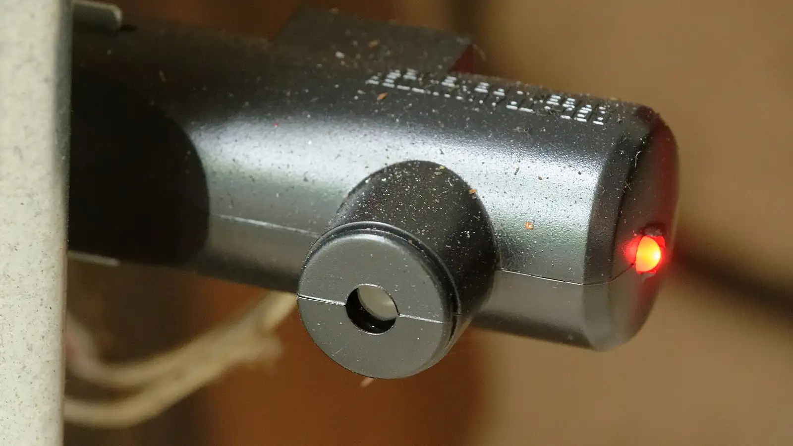 Close-up of a garage door opener safety sensor with its red light on